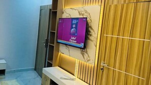 A room with a TV mounted on a wall, a wooden wardrobe, and a small white table. - Studio(S8)@LEKKI PHASE 1, 24/7 Pwr by NgoZiLiving


 (Lekki)