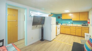 A compact kitchen with a refrigerator, stove, and microwave. There is a small dining area with a table and chairs.