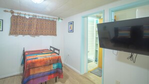 A bedroom with a bed, a television, and a bathroom door.
