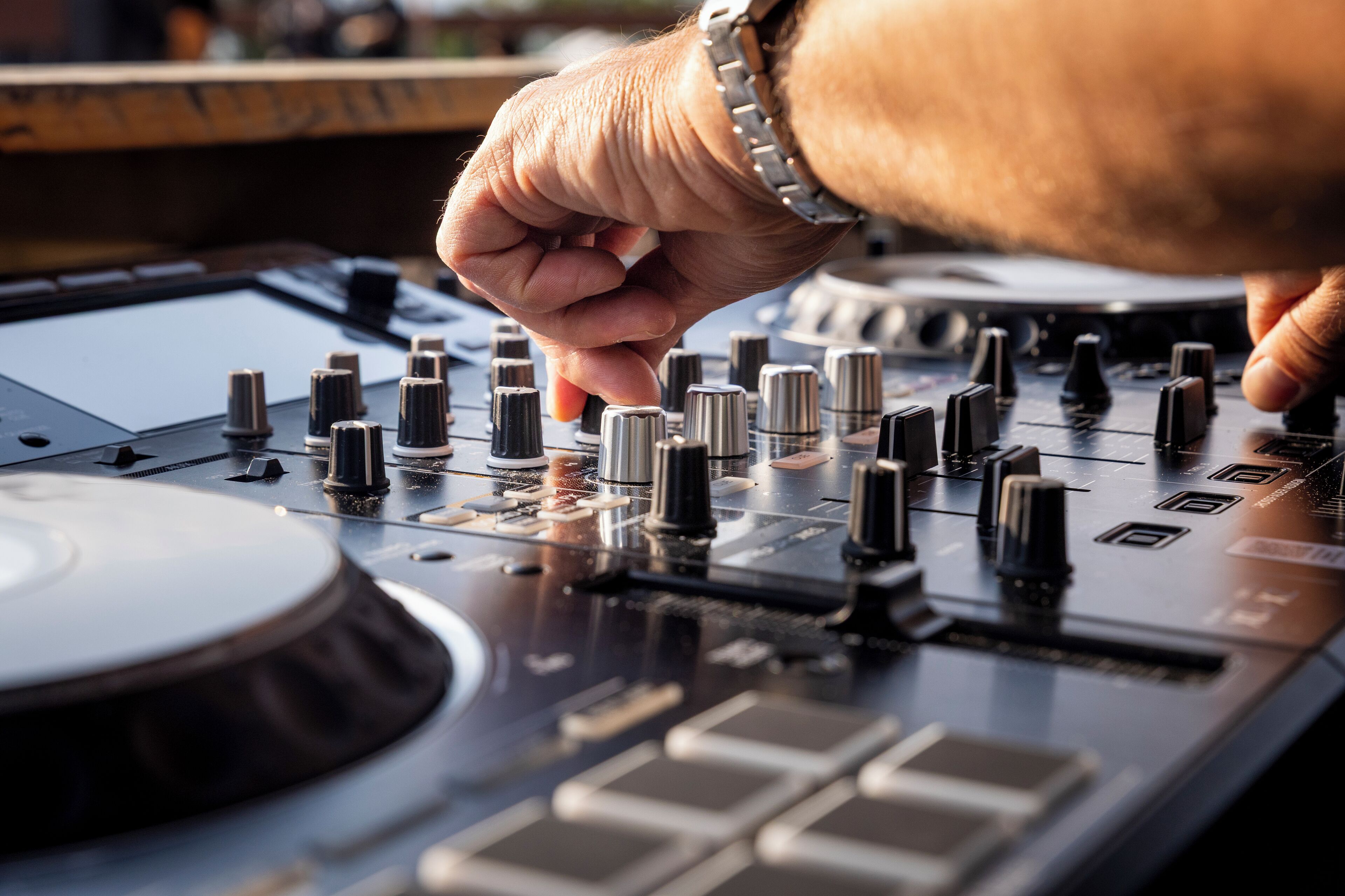 Ein Detailbild eines DJ-Mixers mit mehreren Reglern und Schiebereglern, das auf eine professionelle Audio-Ausstattung hindeutet.