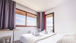 Une chambre d’hôtel avec un lit, un bureau, une chaise et une vue sur le ciel par la fenêtre.