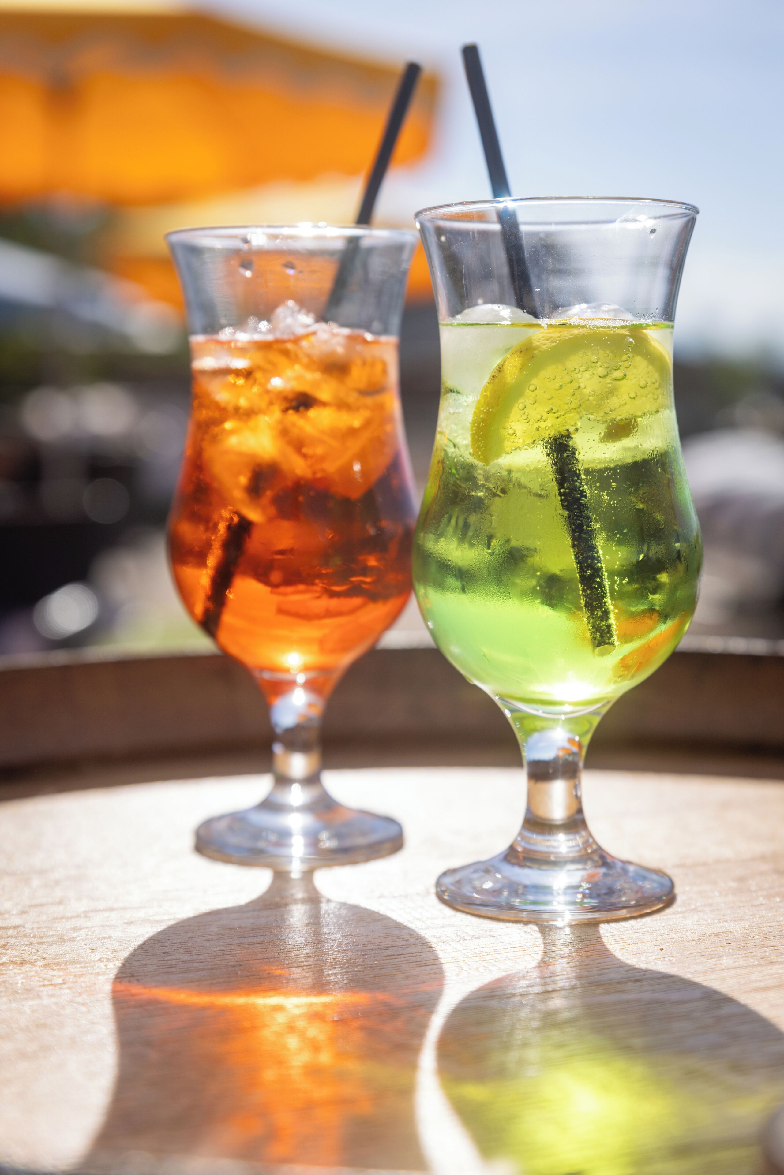 Two glasses of beverages on a reflective surface.
