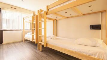 Dormitorio con literas, una escalera de madera, un escritorio y un televisor instalado en la pared.
