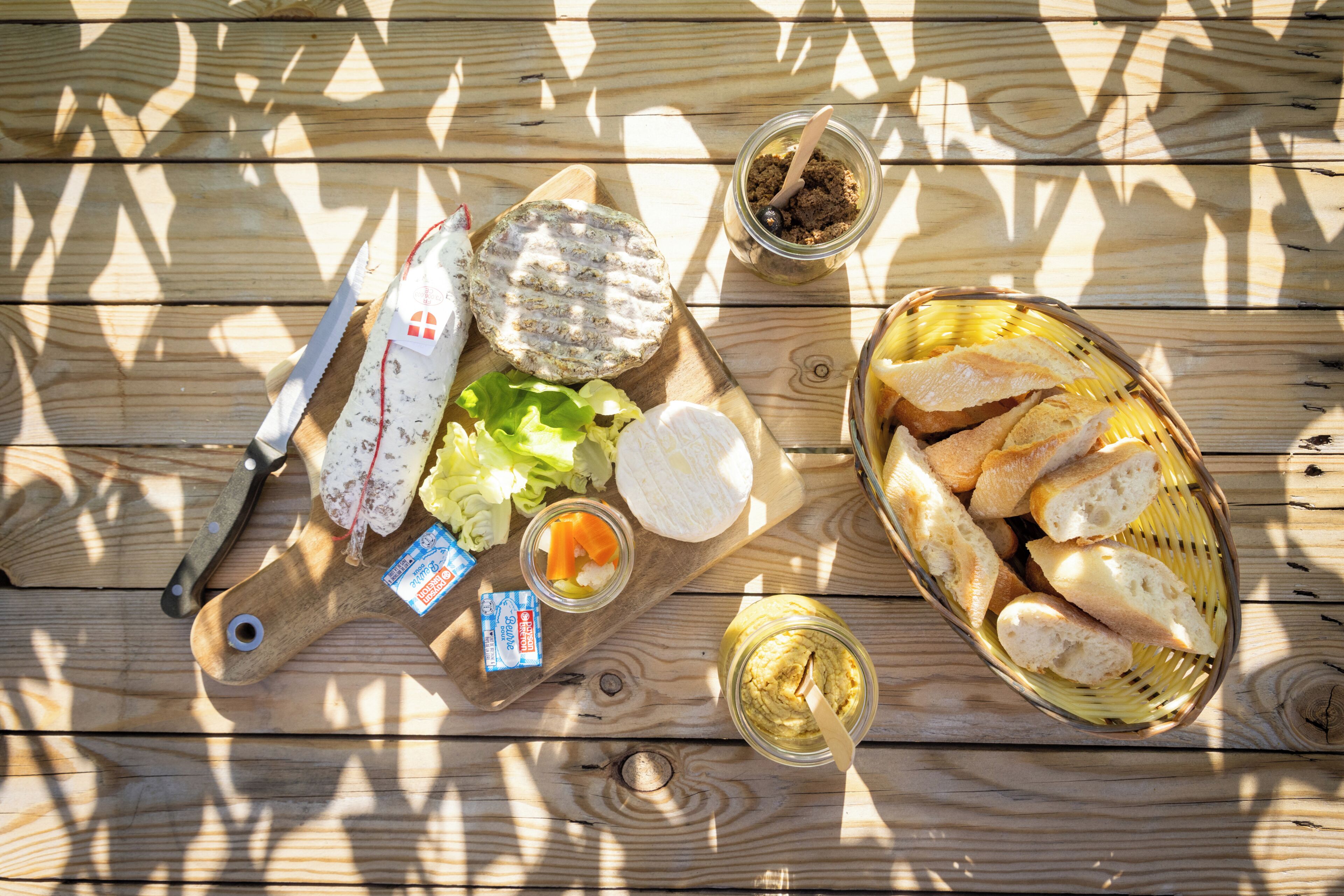 Taula de fusta amb diversos aliments, com ara pa, formatge i condiments.