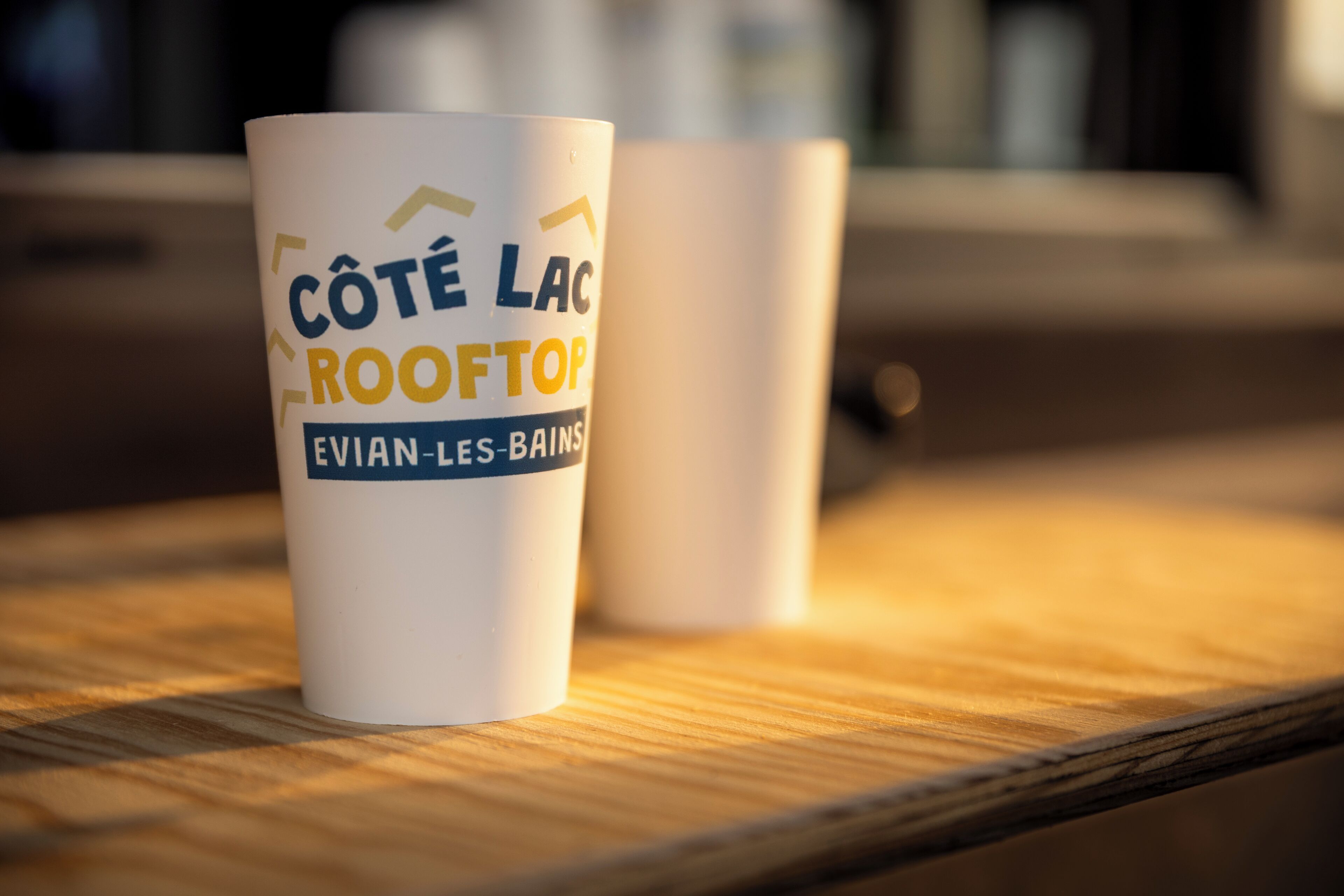 Two white mugs with text on them, placed on a wooden surface.