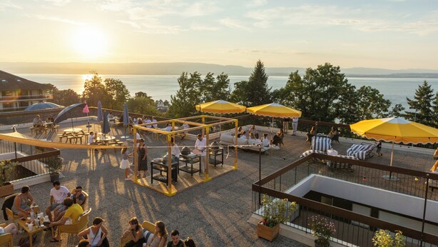 Une terrasse extérieure dotée d’espaces aménagés pour s’asseoir, de parasols et offrant une vue sur l’eau.