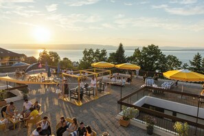 Terraço ao ar livre com áreas de estar, guarda-sóis e vista para a água.