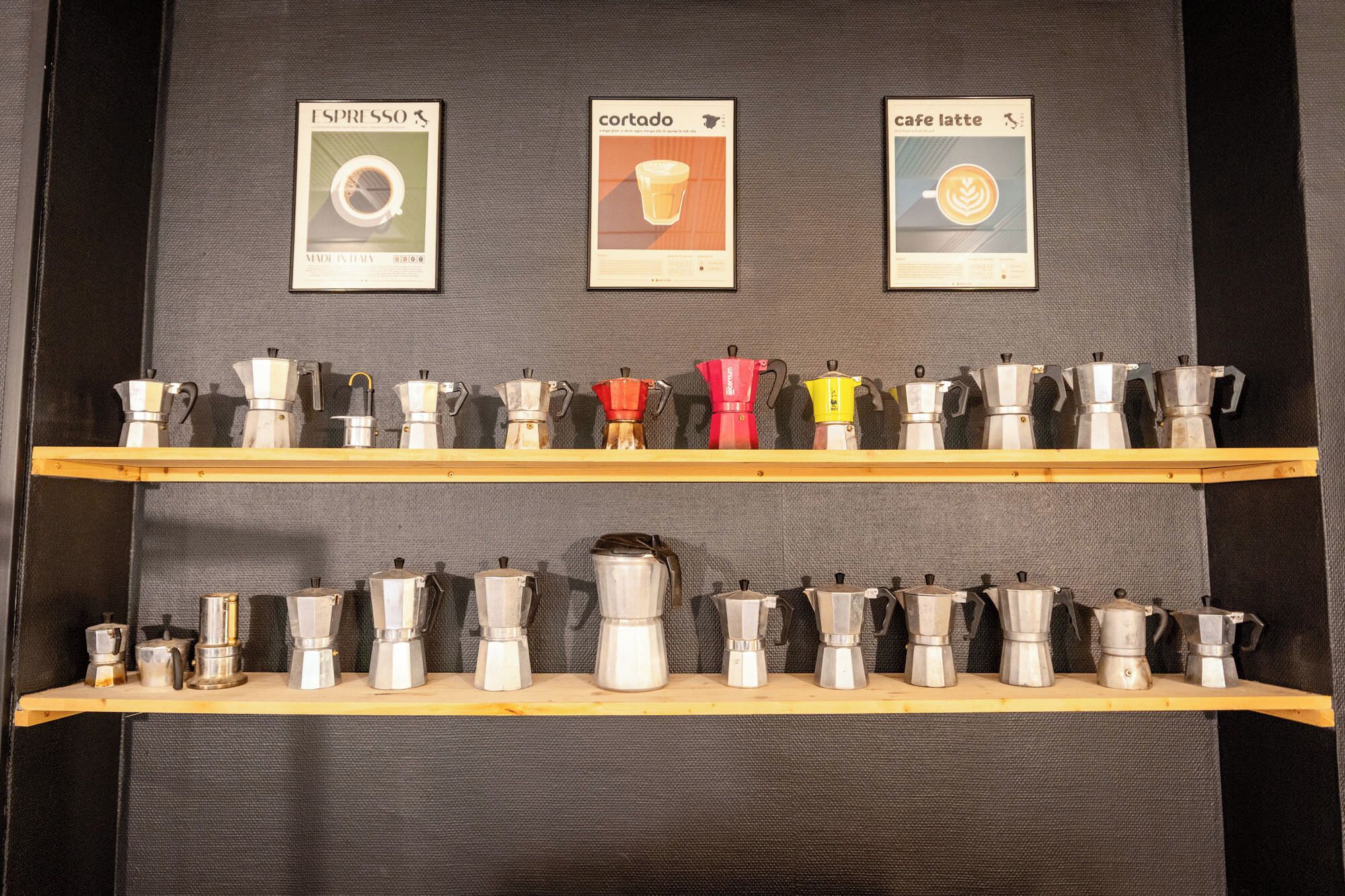 Une exposition de machines à expresso, présentées sur des étagères, avec des panneaux indiquant les différents types de café au-dessus.