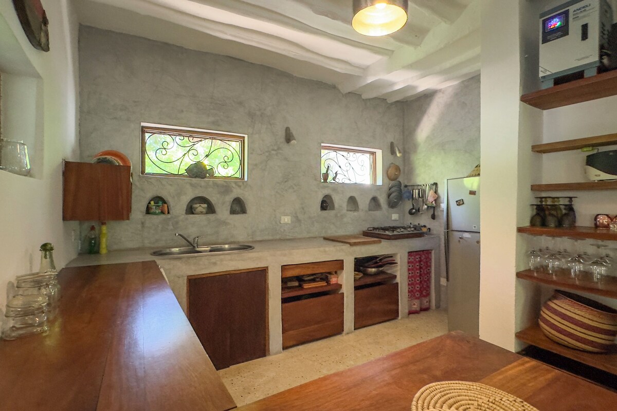 A compact kitchen with a central island, built-in shelves, and a refrigerator.