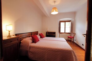 A bedroom with two beds, a wooden dresser, a chair, and a window with a view. - Brunelleschi Suite (Florence)