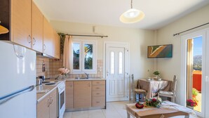 A modern kitchen with wooden cabinets, a dining area with a table and chairs, and a view through a glass door.
