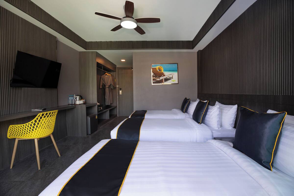 Habitación de hotel con dos camas, televisión, escritorio y una silla.