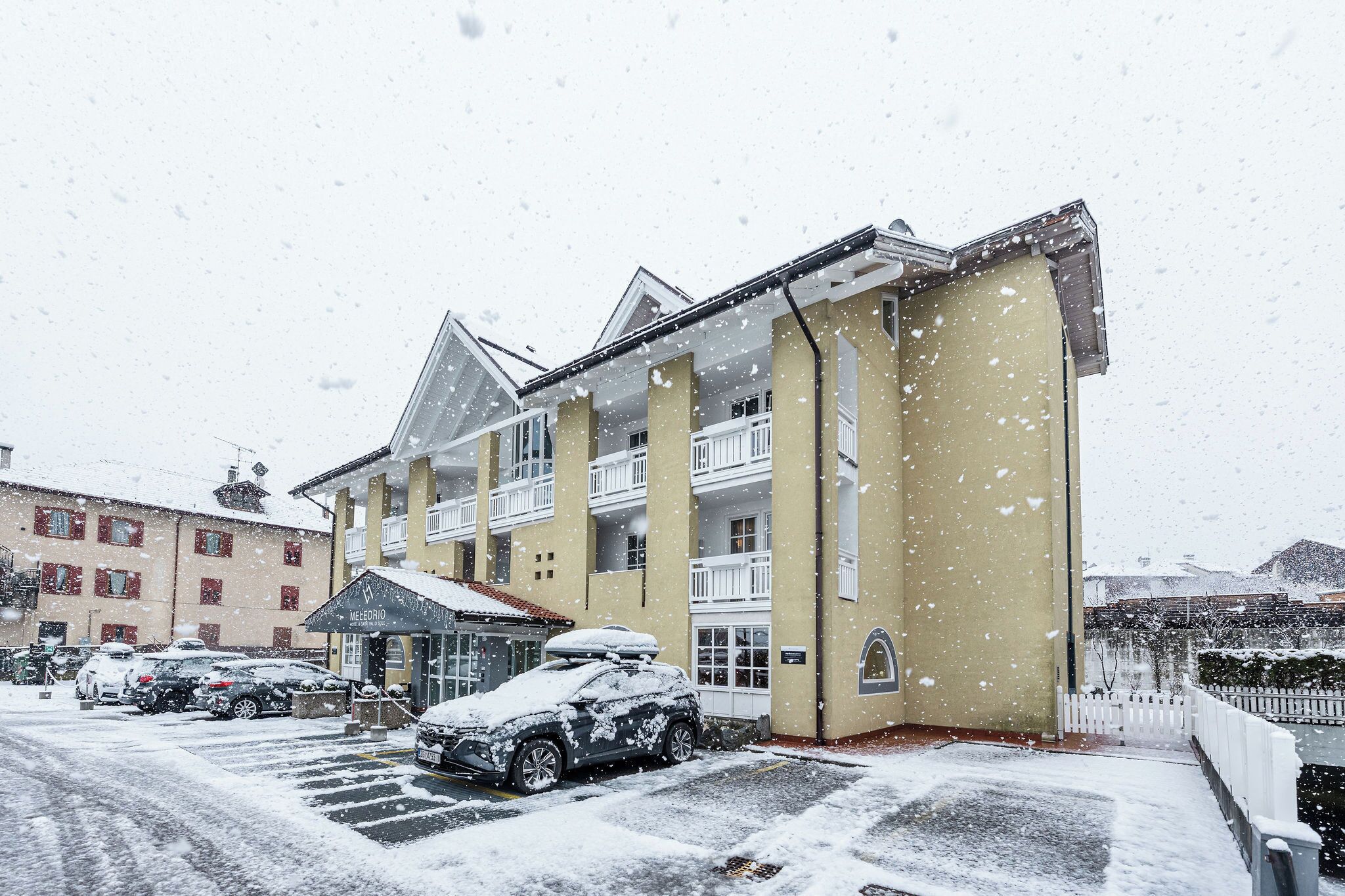 A hotel with multiple floors, a covered entrance, and a parking area with cars.