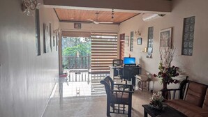 A spacious living area with a wooden ceiling, a dining table with chairs, a sofa, and a TV. - GG Lodge (Mirissa)