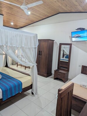 A bedroom with a bed, a wardrobe, a TV, and a ceiling fan. - GG Lodge (Mirissa)