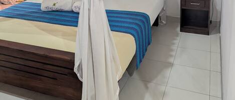 A bedroom with a bed under a white canopy, a bedside table with a lamp, and a patterned rug on the floor.