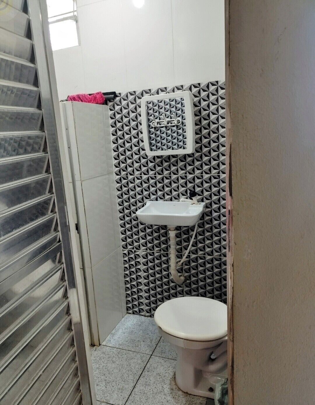 A small bathroom with a toilet, sink, and a shower stall.