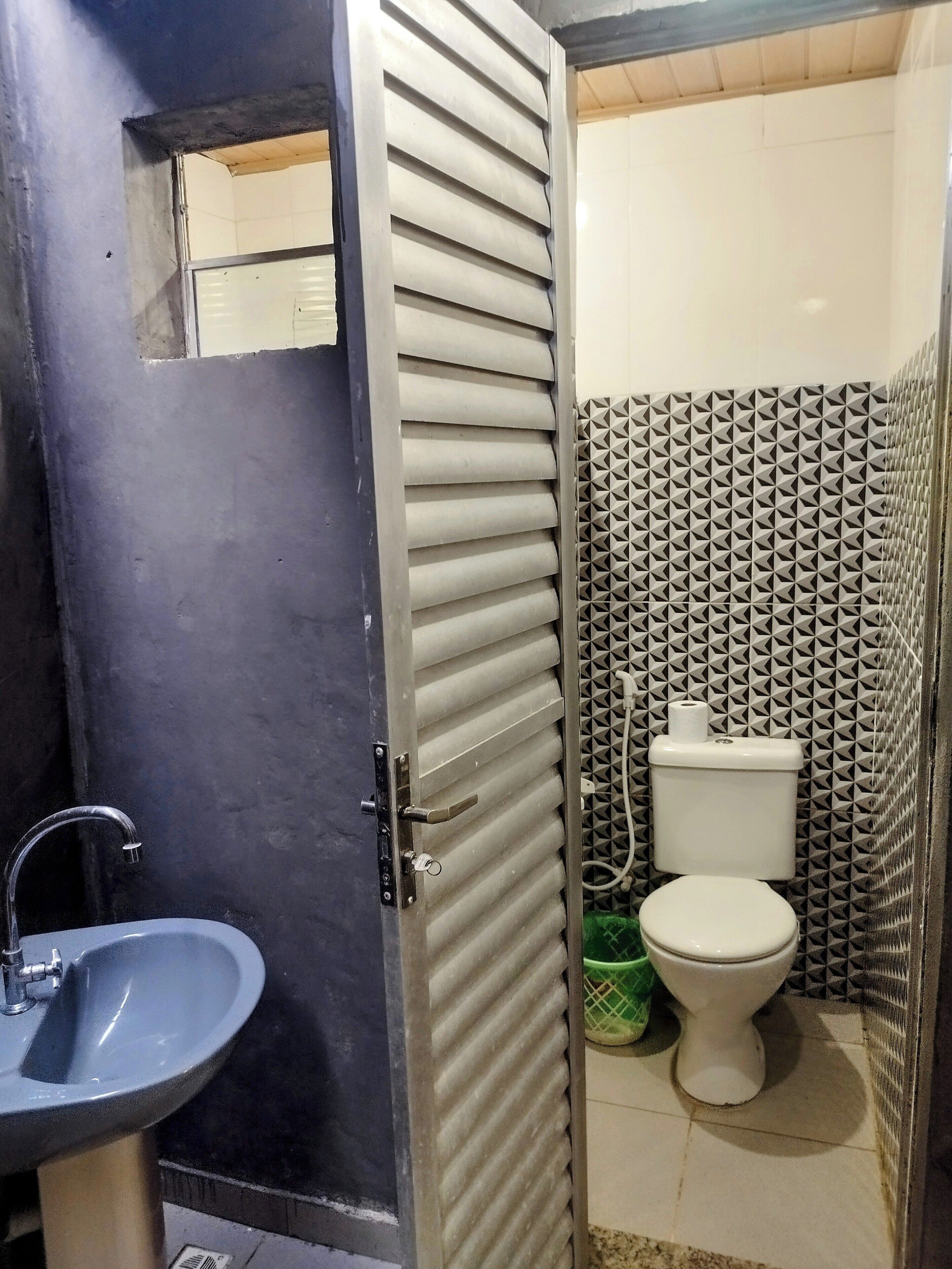 Ein Badezimmer mit Toilette, Waschbecken und einer Tür mit Schlüsselsperre.