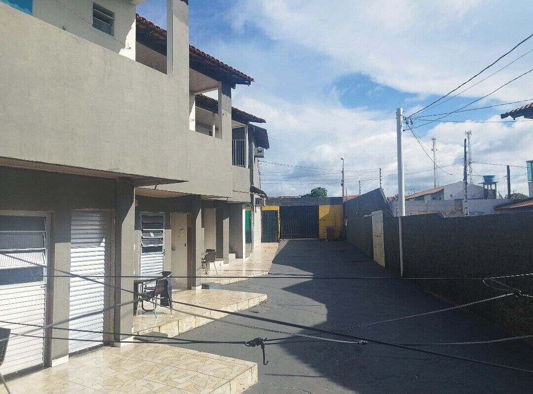 Rua estreita com edifícios em ambos os lados, céu claro e postes de eletricidade.
