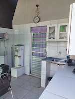 Uma cozinha compacta com micro-ondas, pia e janela com cortinas roxas.