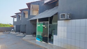 A modern building with a tiled exterior, a covered outdoor seating area, and a visible entrance. - Pousada Temporada no Atalaia (Salinópolis)