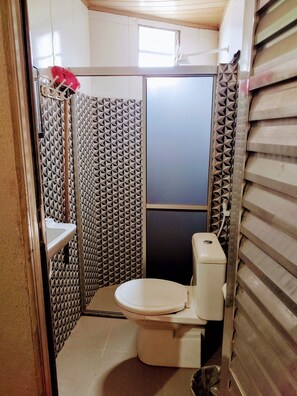 Ein kleines Badezimmer mit Toilette, Waschbecken und Duschbereich.