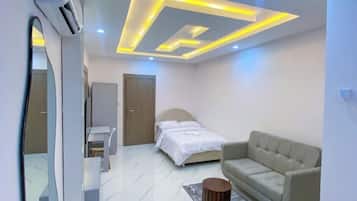 A modern bedroom with a bed, a sofa, a desk, and a mirror.