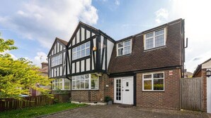Une maison de style Tudor à deux étages, avec une façade en briques et des fenêtres à cadre blanc.