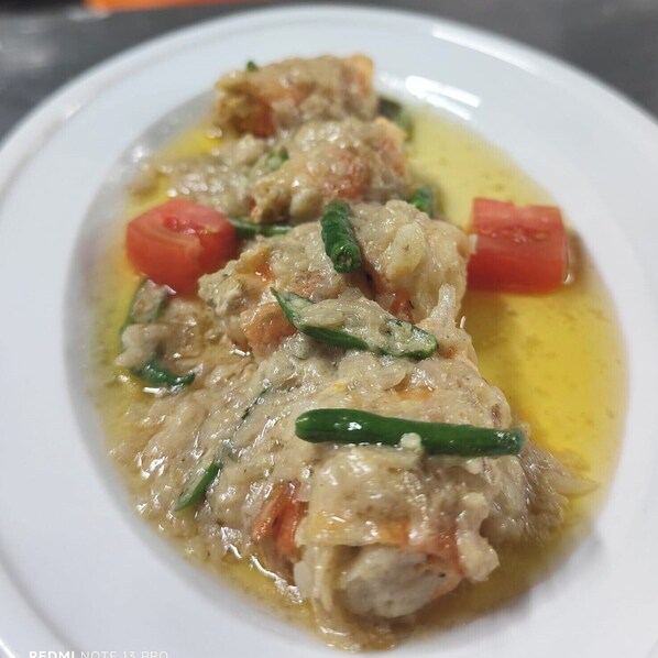 Un plato con pollo, tomates y judías verdes sobre una fuente blanca.