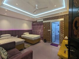 Quarto moderno com duas camas, um sofá, um ventilador de teto e uma porta de vidro deslizante que dá para uma varanda.