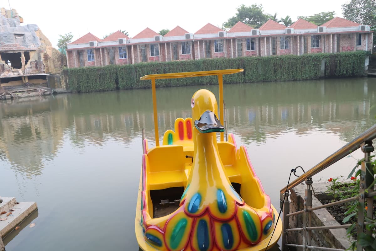 A yellow boat with a peacock design docked at a pier.