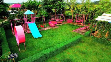 Um parquinho com escorrega e balanços em um jardim exuberante.