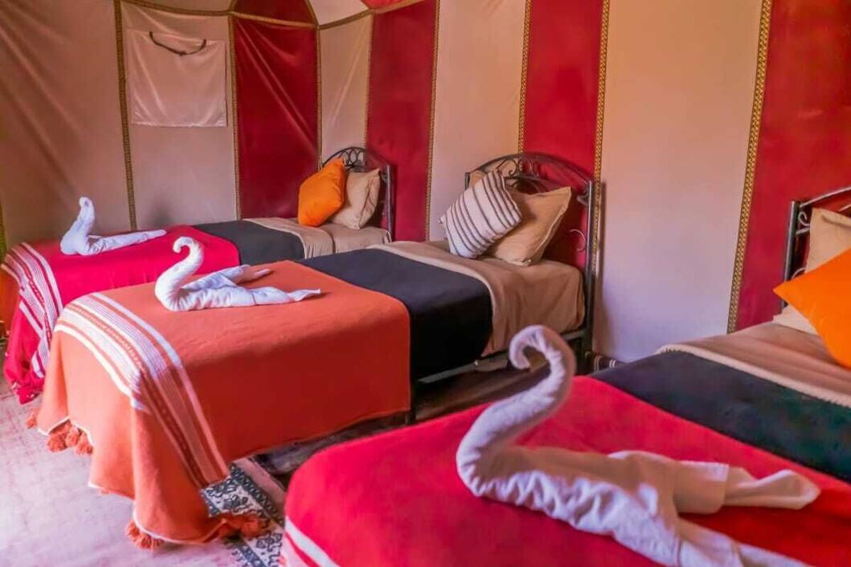 Una habitación con dos camas, cada una con una colcha roja y adornos de cisnes blancos.