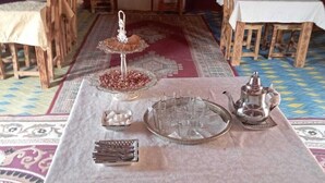 Zona pranzo con tavolo apparecchiato per un pasto, comprensiva di vassoio con bicchieri, piatto con noci, brocchetta d'argento e portacandele.
