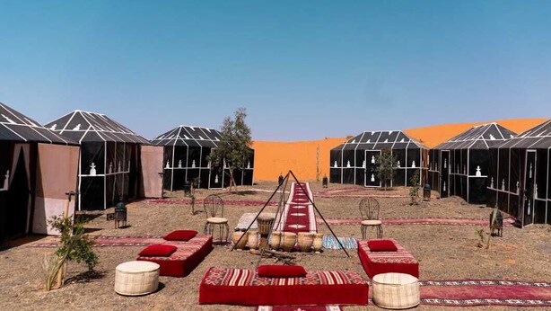Un resort nel deserto con diverse tende, tappeti a motivi rossi e bianchi e un percorso centrale.
