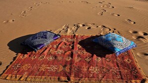 Paesaggio desertico con dune di sabbia e impronte che conducono verso l'orizzonte.