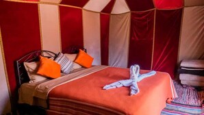 Un letto con una coperta a righe, un cuscino a righe rosse e bianche e un cuscino arancione.