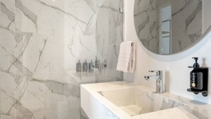 A modern bathroom with a white marble sink, a glass-enclosed shower, and a round mirror. - w* | Urban 2BR w/ Cozy Terrace in Bocagrande (Cartagena de Indias)