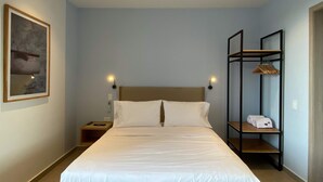 A hotel room with a large bed, two bedside tables, a wall-mounted shelf with towels, and a framed picture on the wall. - w* | Tranquil Loft w/ Great Terrace in Bocagrande (Cartagena de Indias)