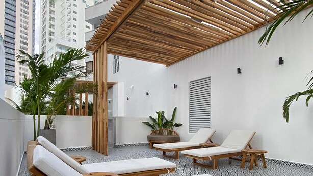 A rooftop lounge area with wooden loungers, potted plants, and a pergola structure. - w* | Tranquil Loft w/ Great Terrace in Bocagrande (Cartagena de Indias)