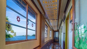 Un pasillo con suelo de madera, ventanas amplias con diseños florales y vista al mar.
