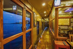 Un couloir doté d’un plancher en bois, de portes en verre et offrant une vue sur la mer.