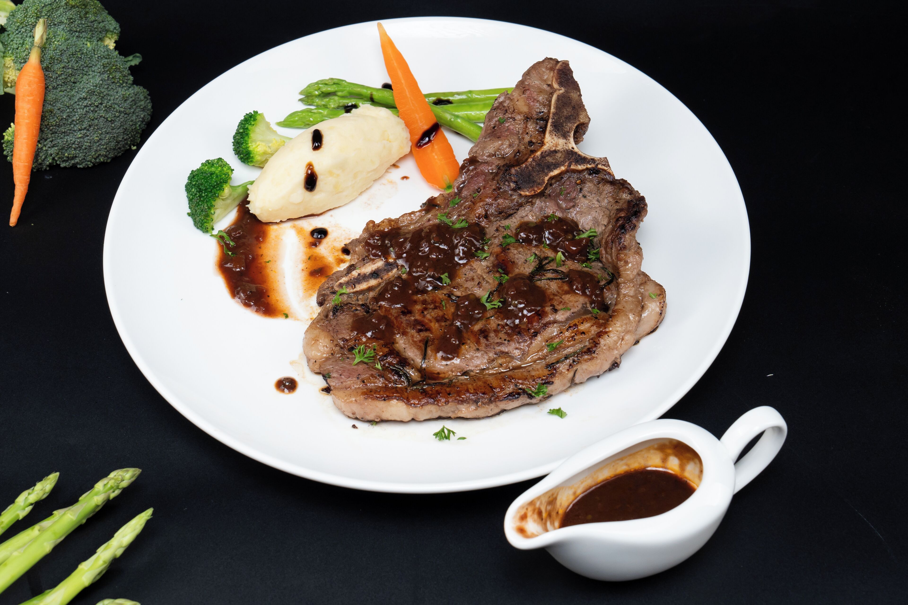 Une assiette contenant un steak, des légumes et de la sauce.