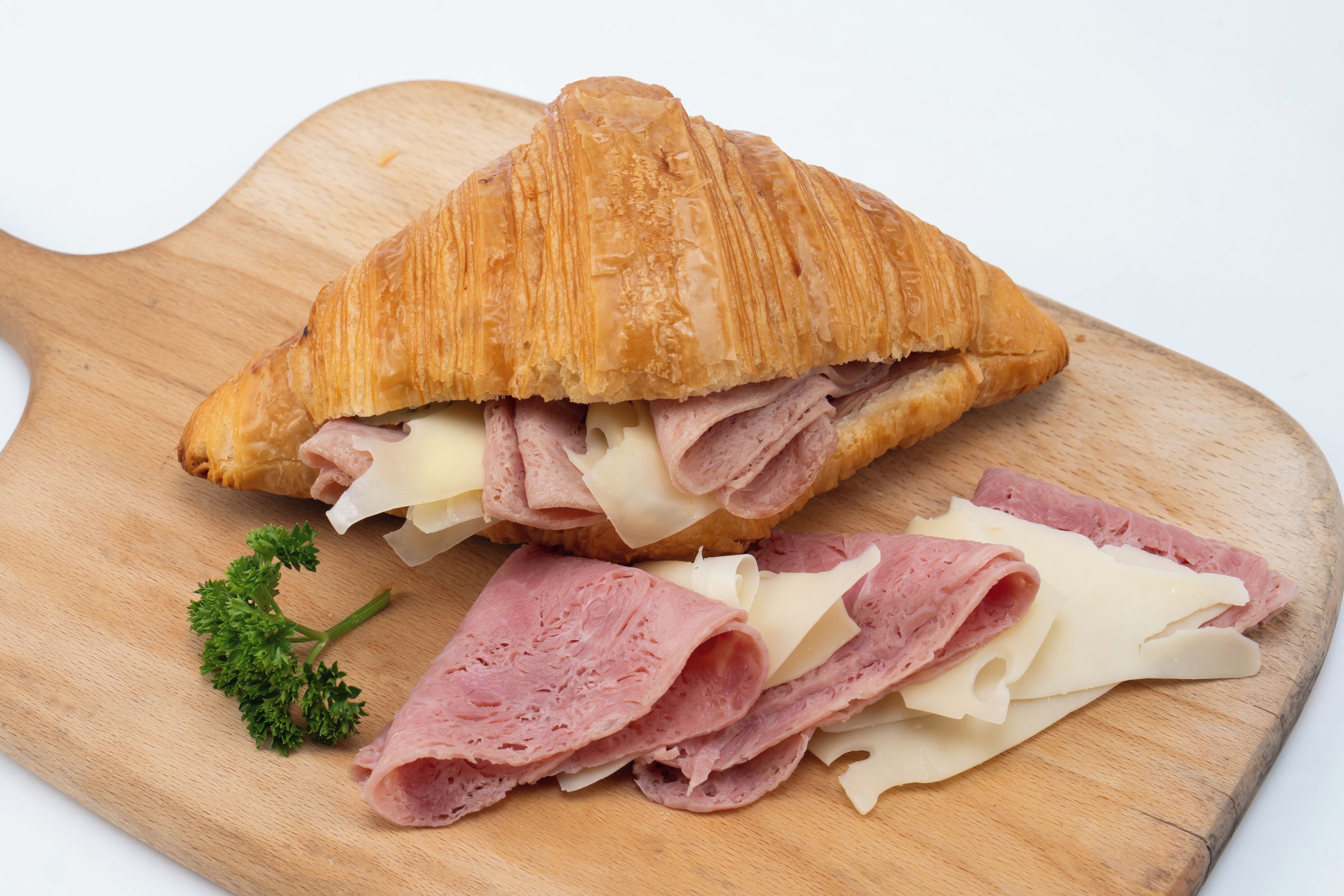 A sandwich on a wooden board with a piece of parsley.