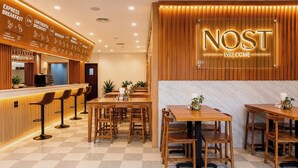 A restaurant with a wooden interior, a menu board, and a 'NOST' welcome sign. - Angkor Mansion & Residence (Siem Reap)