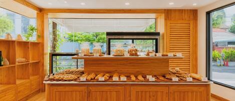 Mostrador de panadería con diferentes productos horneados y vistas a zonas verdes al exterior.