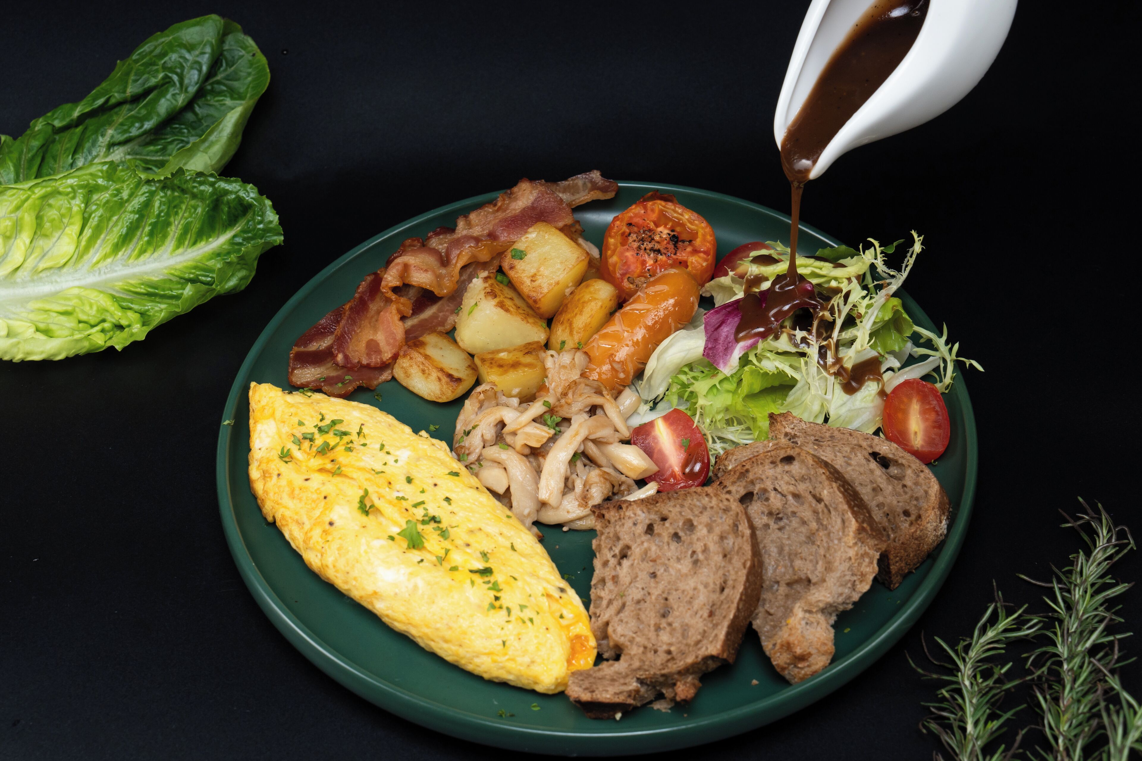 A plate of breakfast food including eggs, bacon, potatoes, mushrooms, and a salad.