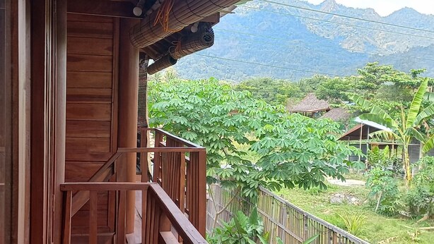 A wooden balcony with a view of a mountainous landscape. - Sandyakala Borobudur (Borobudur)
