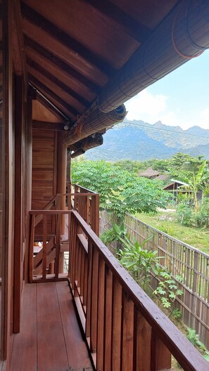 A wooden balcony with a view of a mountainous landscape. - Sandyakala Borobudur (Borobudur)