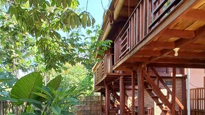 A wooden deck with a stone pathway leading to a building with a balcony. - Sandyakala Borobudur (Borobudur)